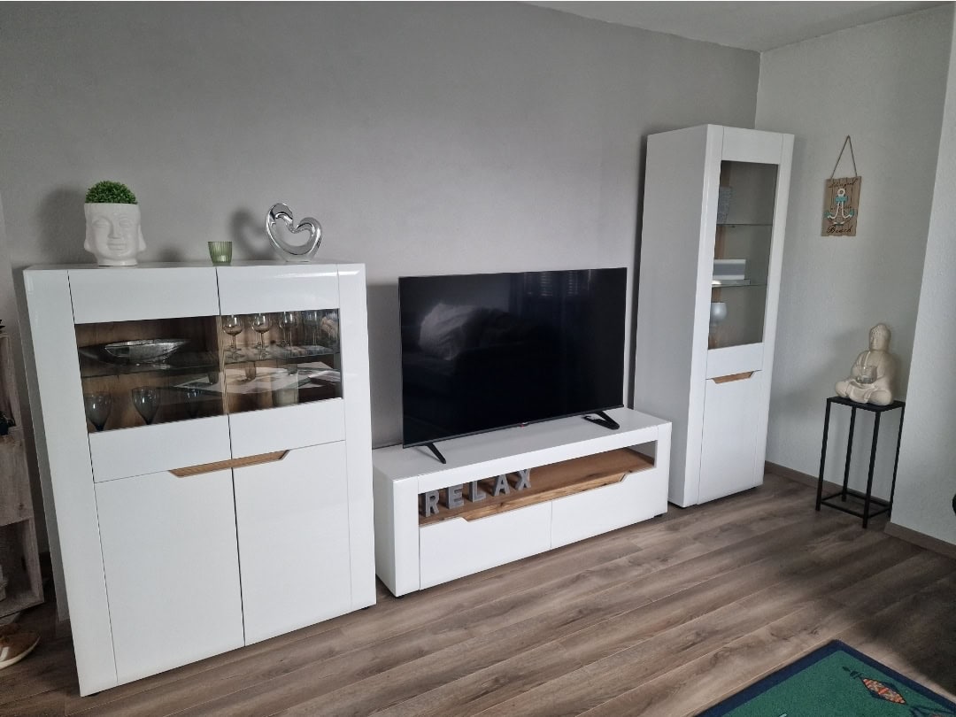 Modernes Wohnzimmer mit weißen Möbeln und Flachbildfernseher.