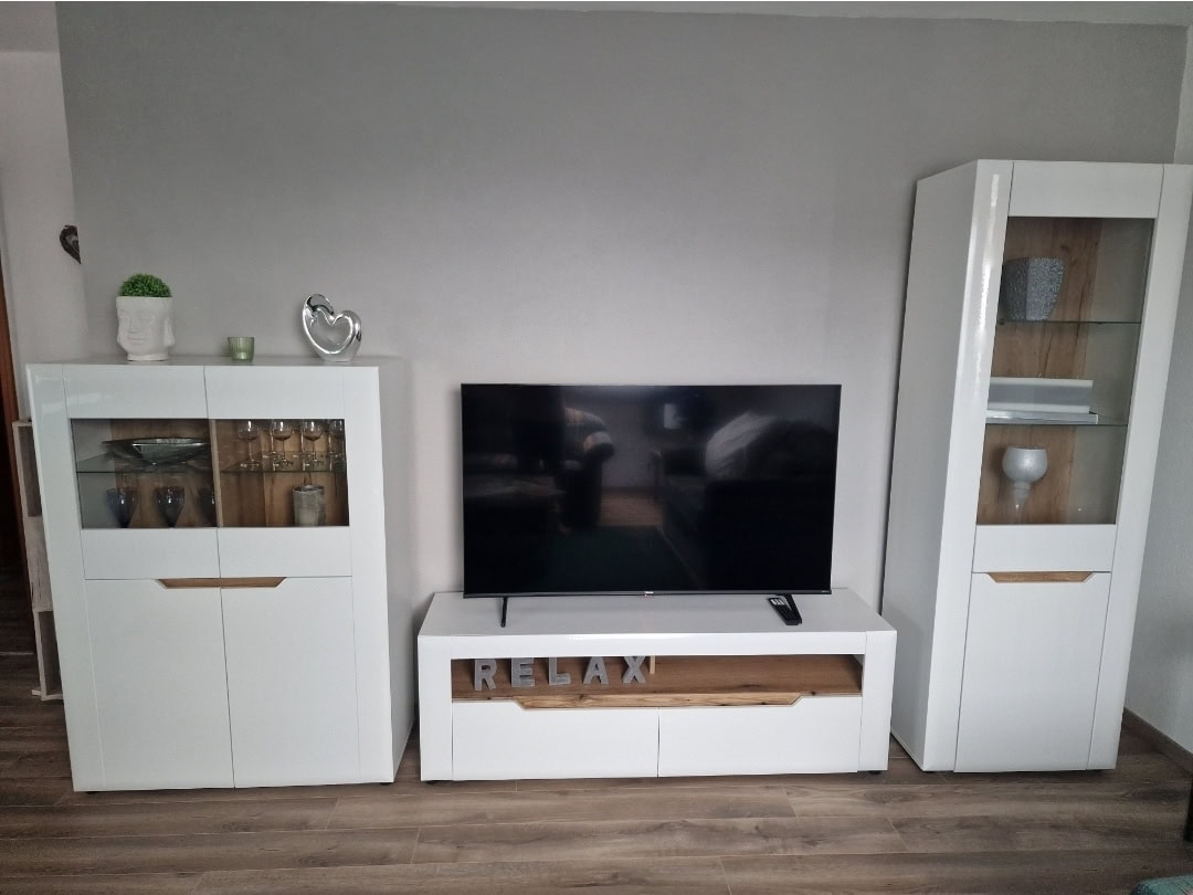 Moderne TV-Ecke mit Flachbildschirm und stilvollen weißen Möbeln.