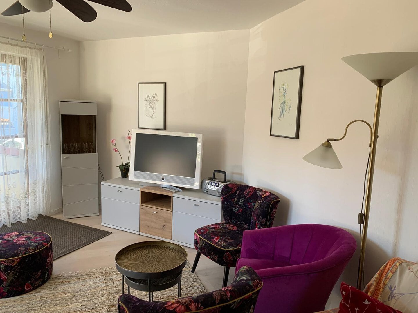 Modernes Wohnzimmer mit bunten Sesseln, Fernseher und Dekoration.