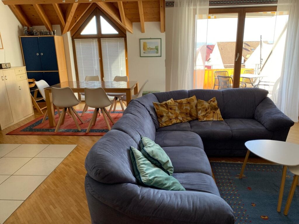 Helles Wohnzimmer mit Sofa, Balkon und Blick auf Bodensee-Umgebung.