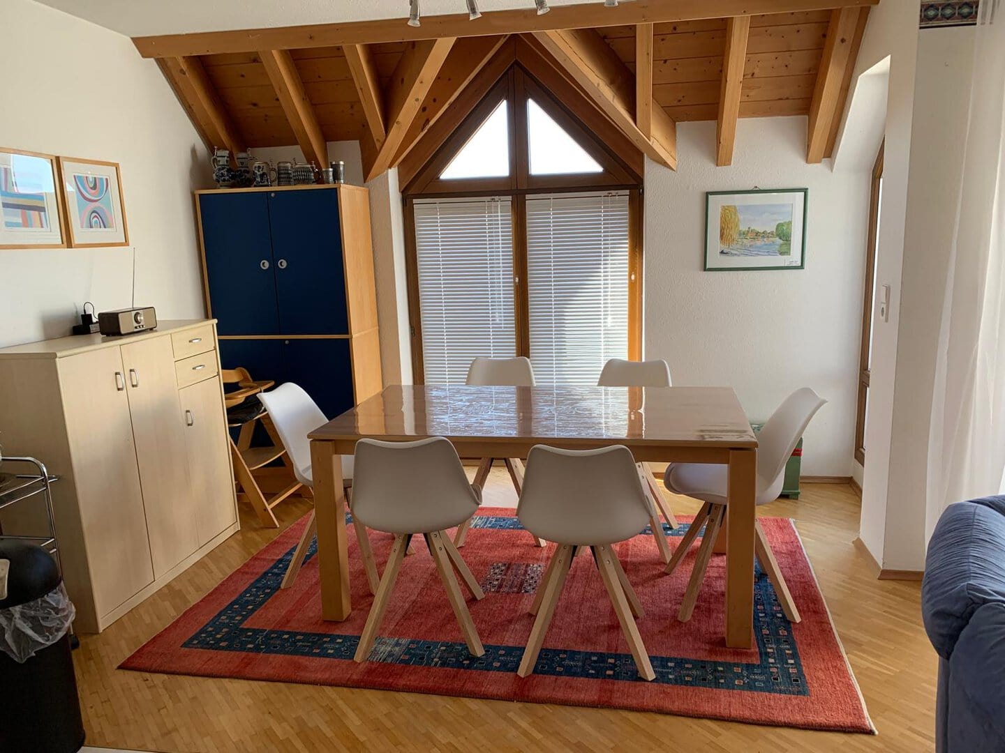 Heller Essbereich mit Holztisch und Stühlen unter Dachbalken.