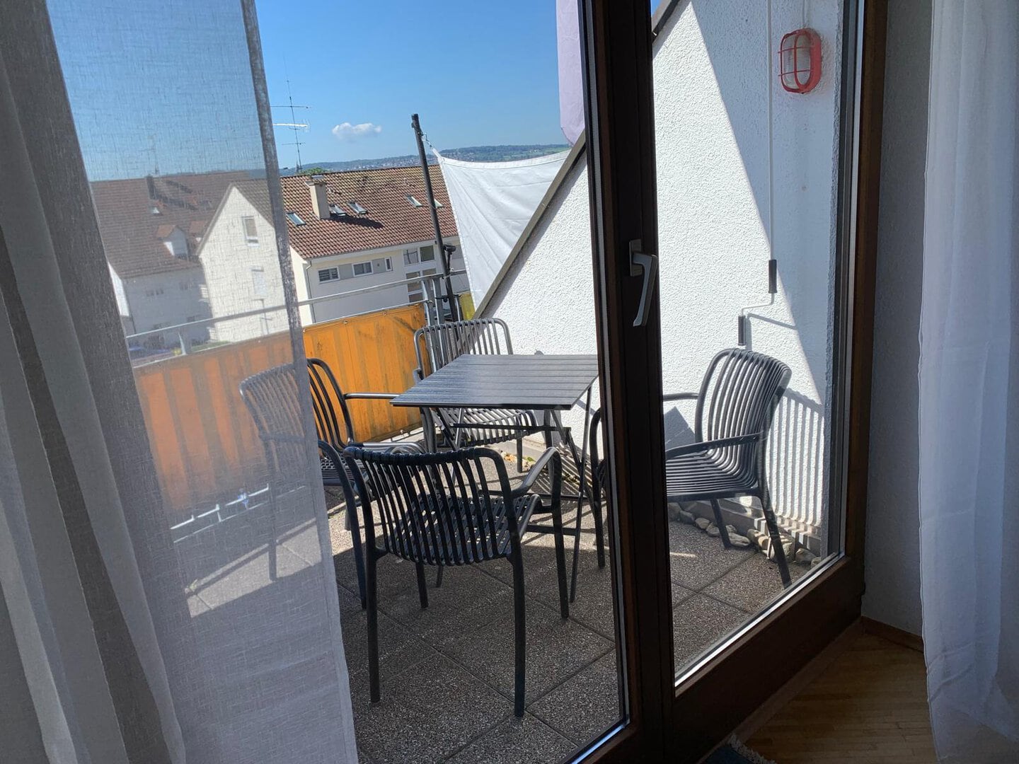 Balkon mit Tisch und Stühlen, Blick auf Bodensee und Berge.